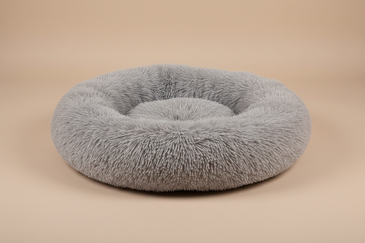 light grey coloured, plush long pile donut cat bed, with beige photography background
